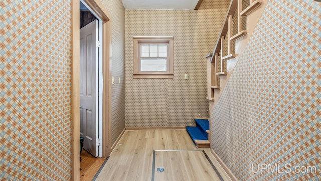 corridor with baseboards, wood finished floors, and wallpapered walls