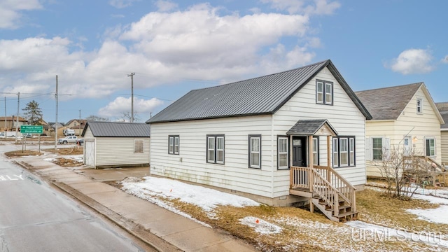 view of front facade featuring metal roof, an outdoor structure, and a shed