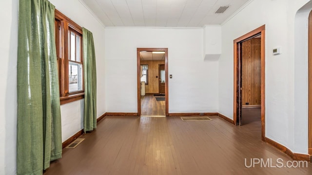 spare room with crown molding, visible vents, arched walkways, and wood finished floors