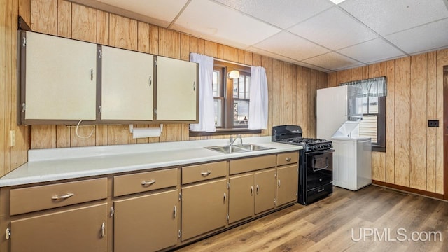 kitchen with light countertops, wood walls, a sink, and black gas stove