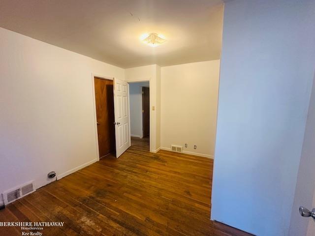 spare room with wood finished floors, visible vents, and baseboards