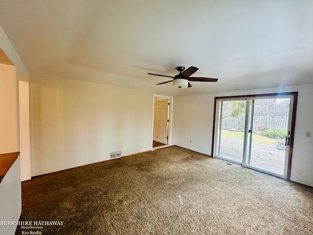 carpeted spare room with visible vents and a ceiling fan