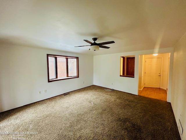 carpeted spare room featuring a ceiling fan