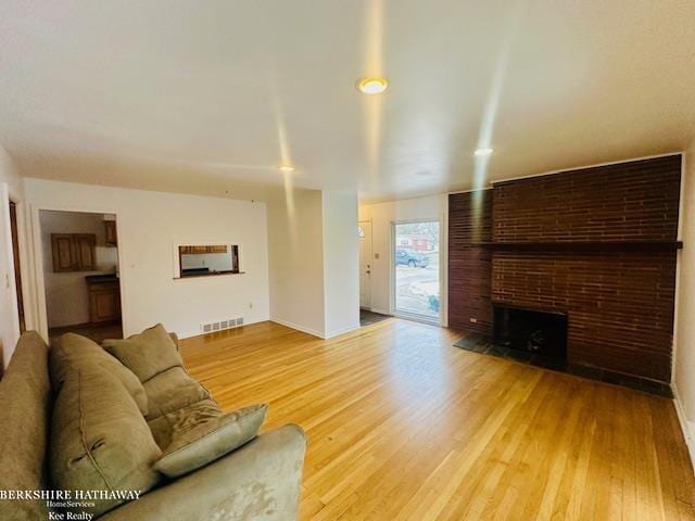 living room featuring light wood-style floors, visible vents, and a fireplace