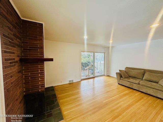 unfurnished living room featuring wood finished floors, visible vents, and baseboards