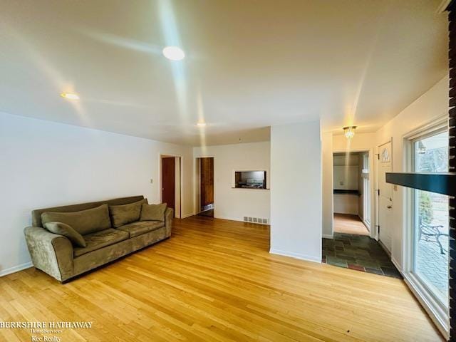 unfurnished living room featuring light wood finished floors, baseboards, and visible vents