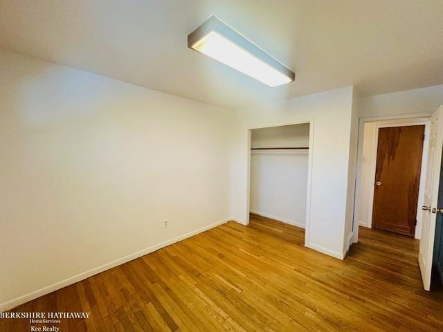 unfurnished bedroom featuring a closet, baseboards, and wood finished floors