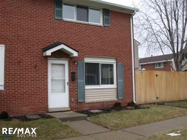 view of front facade featuring brick siding and fence