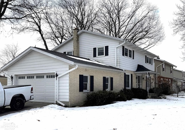 view of front of house with brick siding, a chimney, and an attached garage