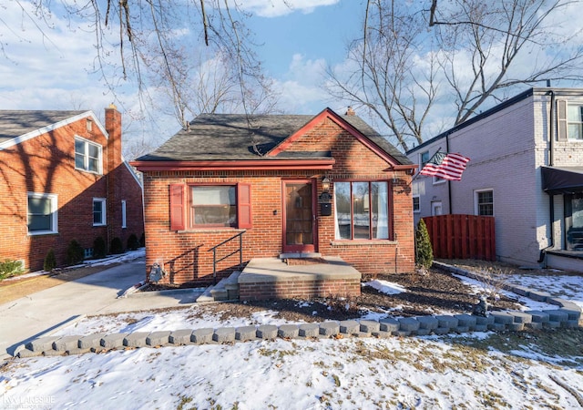 view of front of property featuring brick siding, fence, and driveway