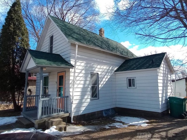 view of side of home with a shingled roof and a chimney