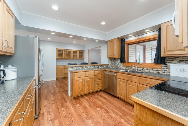 kitchen featuring dark countertops, light wood-style flooring, appliances with stainless steel finishes, ornamental molding, and a sink