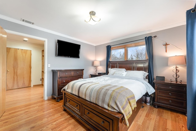 bedroom featuring light wood-type flooring, visible vents, crown molding, and baseboards