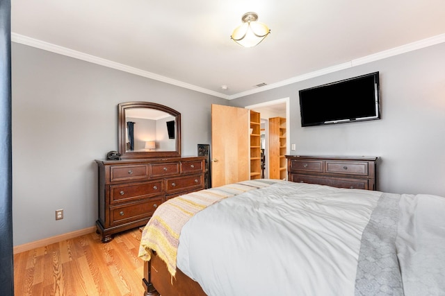 bedroom with visible vents, baseboards, a walk in closet, crown molding, and light wood-style floors