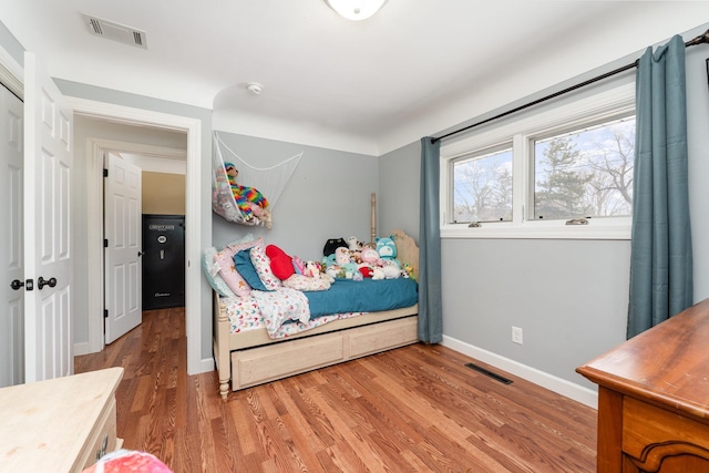 bedroom with wood finished floors, visible vents, and baseboards