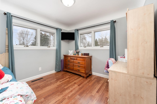 bedroom with light wood-style flooring, multiple windows, and baseboards