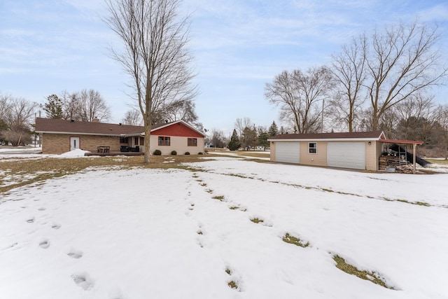 yard covered in snow featuring an outbuilding and a detached garage