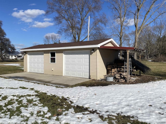 snow covered garage with a detached garage