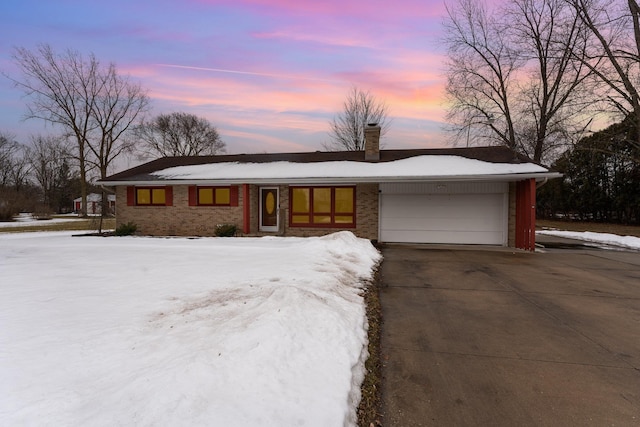 view of front facade with driveway, a chimney, and an attached garage