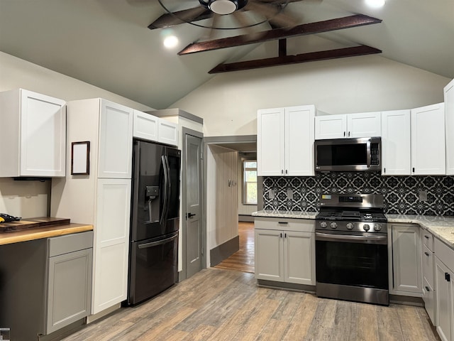 kitchen with appliances with stainless steel finishes, a baseboard radiator, light wood-style flooring, and decorative backsplash