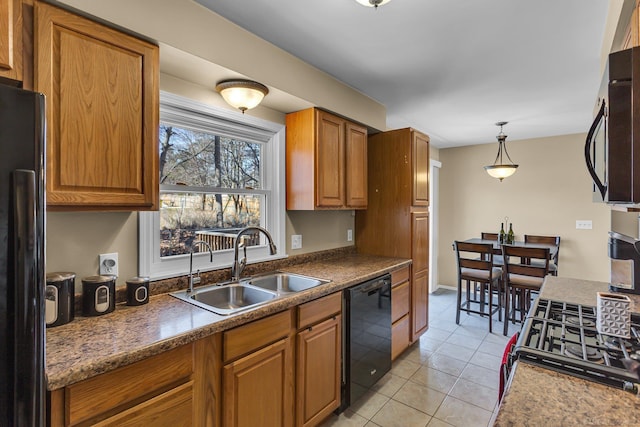 kitchen featuring pendant lighting, light tile patterned floors, brown cabinetry, a sink, and black appliances