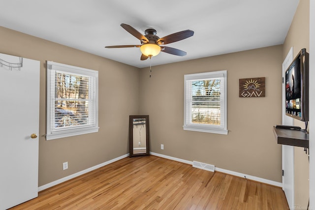 empty room with light wood-style floors, baseboards, and visible vents