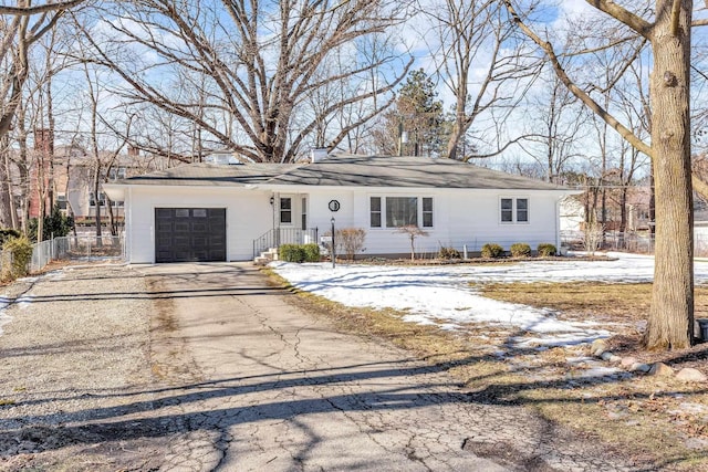 ranch-style home featuring a garage, driveway, and fence