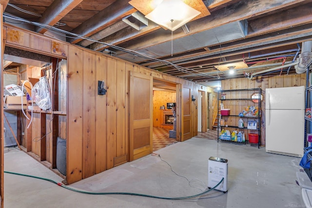 unfinished below grade area featuring freestanding refrigerator and wooden walls