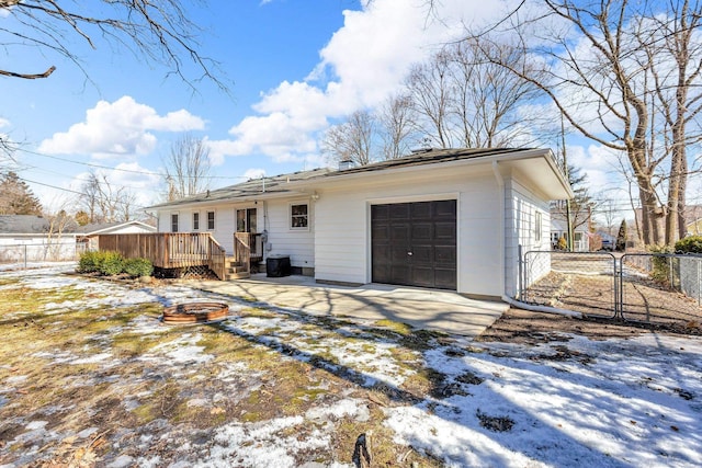 view of front facade featuring driveway, a garage, a gate, fence, and a wooden deck