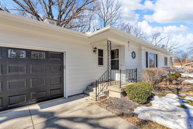 view of exterior entry featuring a garage and concrete driveway