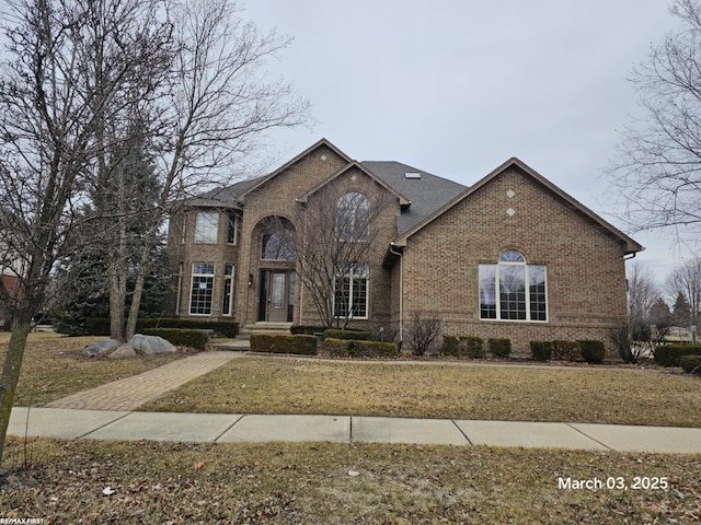 traditional-style house featuring brick siding and a front lawn