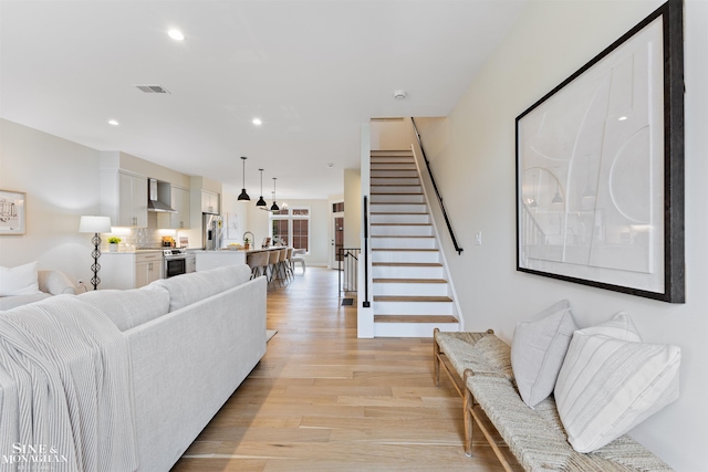 living room with light wood-style floors, visible vents, stairway, and recessed lighting