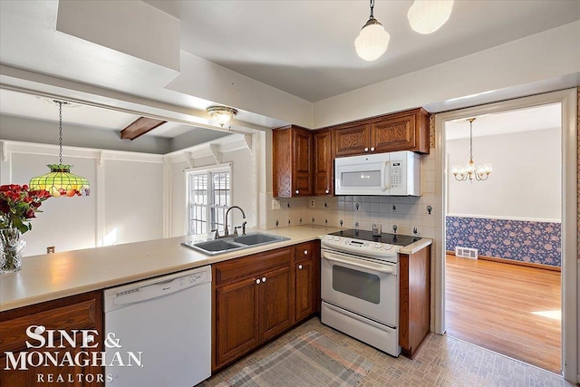 kitchen with white appliances, visible vents, a sink, and decorative light fixtures