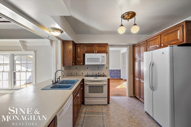 kitchen featuring white appliances, a sink, light countertops, tasteful backsplash, and brown cabinetry