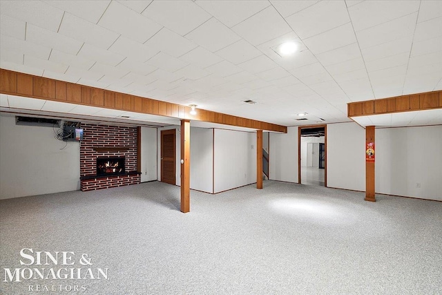 finished below grade area featuring stairs, carpet, a fireplace, and wooden walls