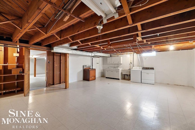 finished below grade area with washer and clothes dryer, a sink, and tile patterned floors