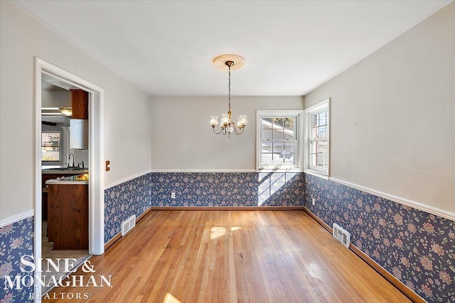 unfurnished dining area featuring wallpapered walls, visible vents, and wainscoting