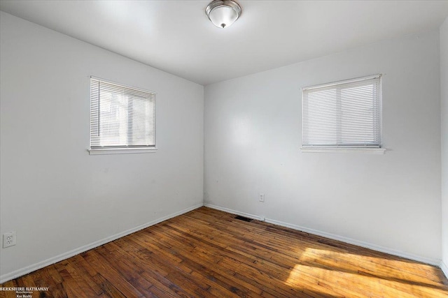 unfurnished room with hardwood / wood-style flooring, visible vents, and baseboards