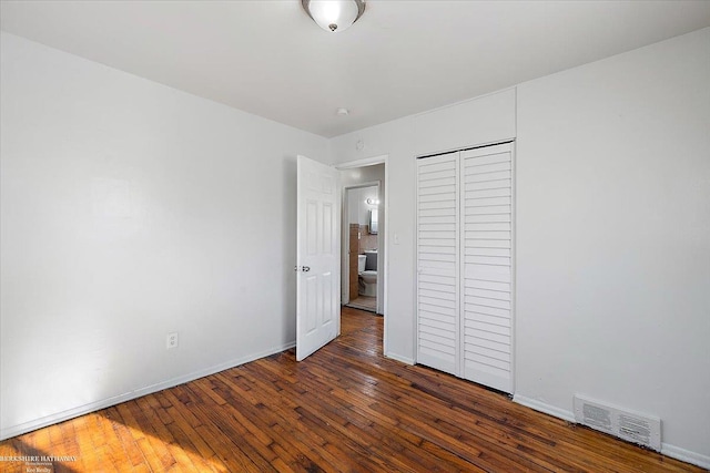 unfurnished bedroom featuring a closet, visible vents, baseboards, and hardwood / wood-style floors