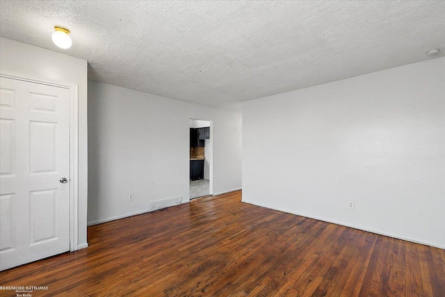 spare room with hardwood / wood-style flooring, visible vents, and a textured ceiling