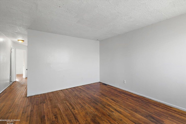 spare room featuring visible vents, baseboards, a textured ceiling, and hardwood / wood-style floors