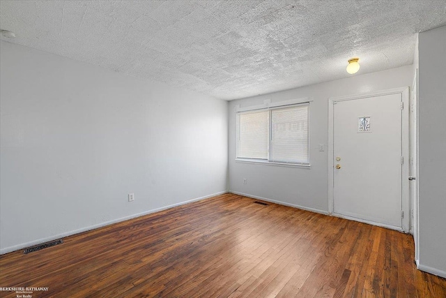 foyer entrance with visible vents, a textured ceiling, and hardwood / wood-style flooring