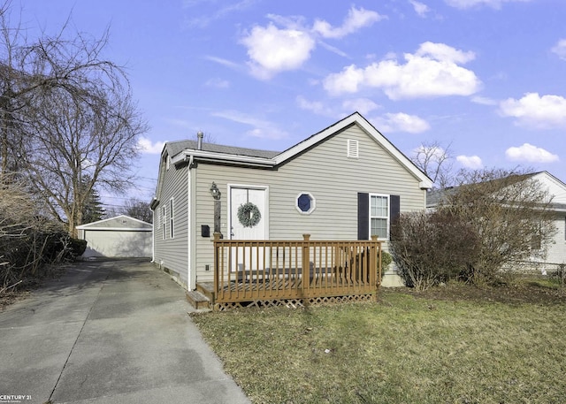 view of front facade featuring a wooden deck, a front lawn, and an outbuilding