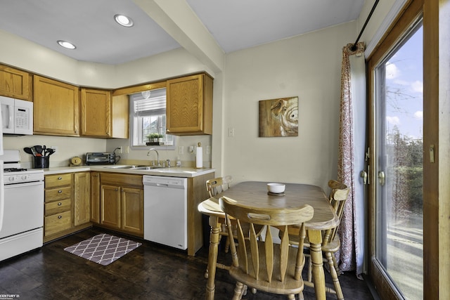 kitchen featuring dark wood-style flooring, brown cabinets, light countertops, a sink, and white appliances