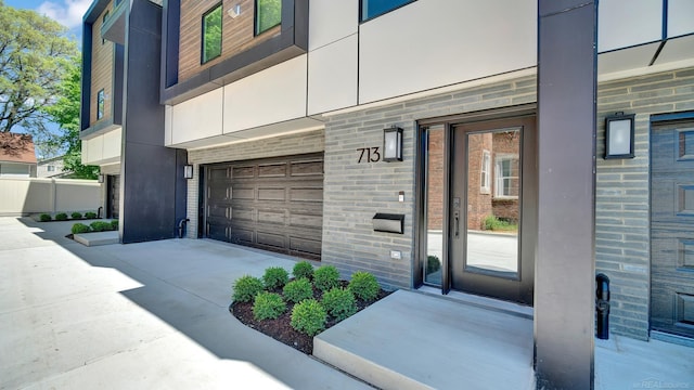 property entrance featuring a garage, brick siding, driveway, and stucco siding