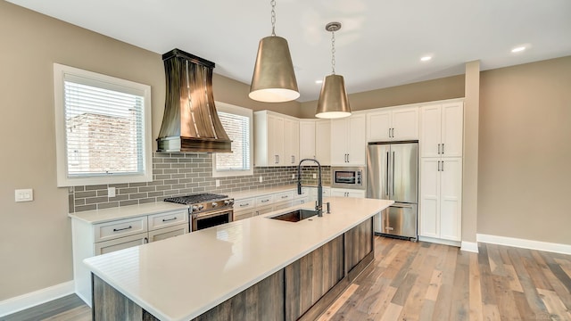 kitchen with premium appliances, light countertops, backsplash, a sink, and premium range hood