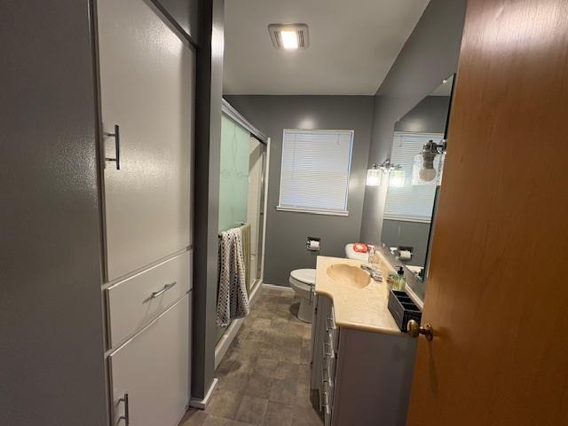 full bath featuring toilet, a stall shower, baseboards, and vanity