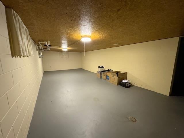 finished below grade area featuring concrete block wall and a textured ceiling