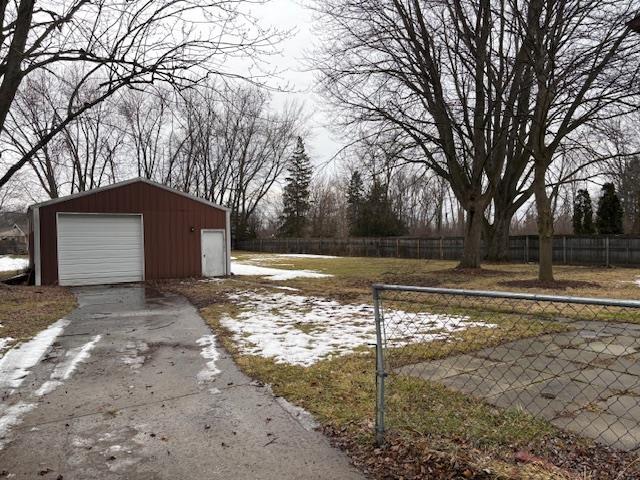 view of yard with a garage, driveway, fence, and an outdoor structure