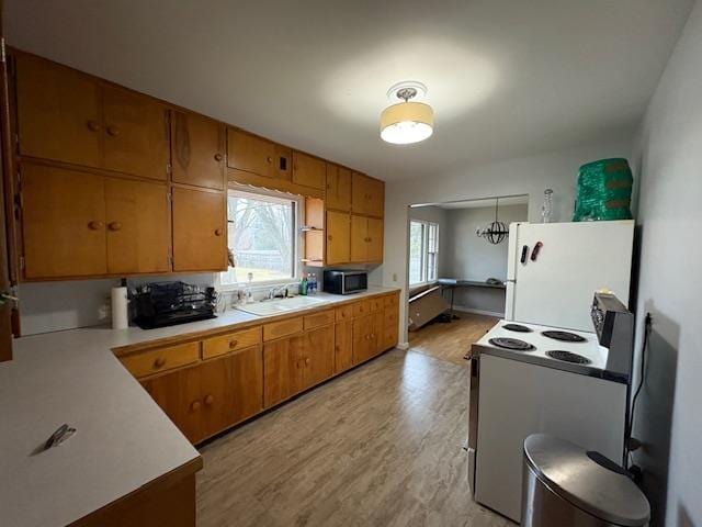 kitchen with brown cabinets, white appliances, light countertops, and a sink